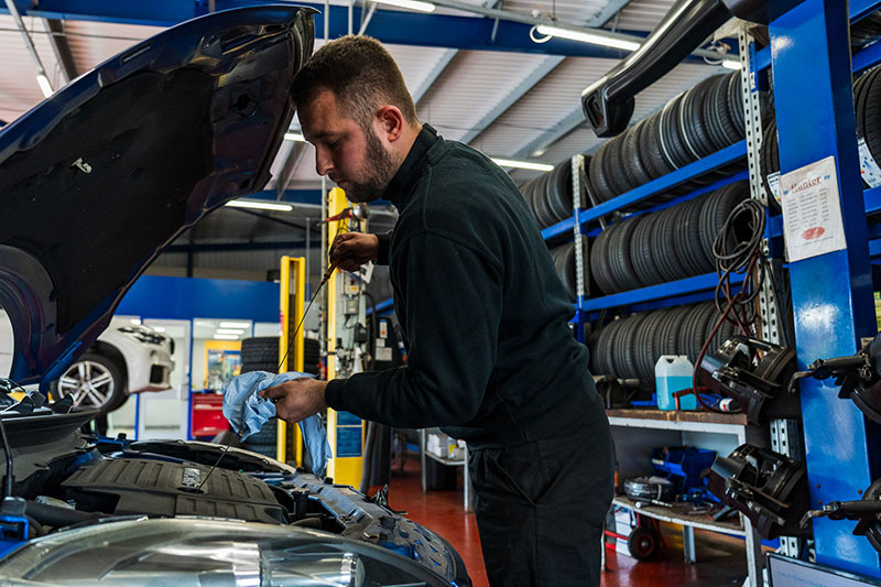 Kwik Fit employee checking oil